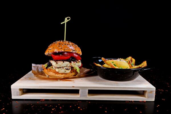 Burger halloumi cu sos calipso, si iceberg, rosii si castrevete, insotit de cartofi prajiti cu usturoi si parmezan